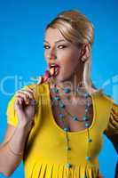 Blond woman in yellow on blue with candy