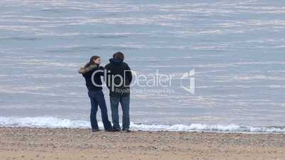 Young teenage couple whale watching from beach