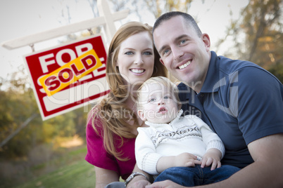 Happy Young Family in Front of Sold Real Estate Sign