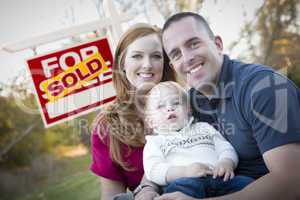 Happy Young Family in Front of Sold Real Estate Sign