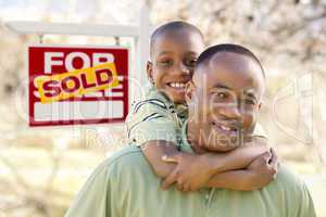 Father and Son In Front of Sold Real Estate Sign