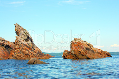 Rocks in the blue sea, illuminated by the sun. Background.