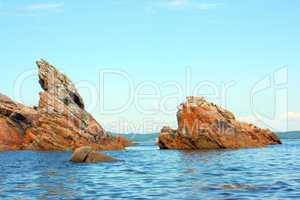 Rocks in the blue sea, illuminated by the sun. Background.