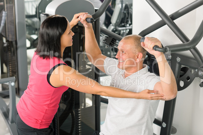 Fitness center trainer assist man exercise back