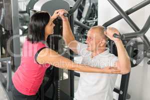 Fitness center trainer assist man exercise back