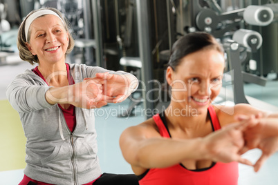 Two women at gym stretch out