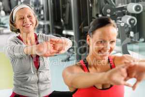 Two women at gym stretch out