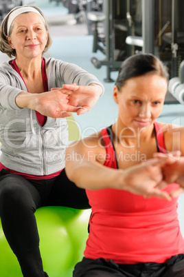 Two women at gym stretch out