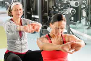 Two women at gym stretch out