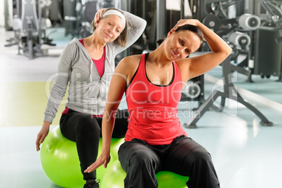 Senior woman with trainer stretching fitness ball