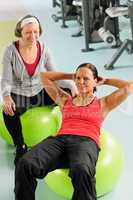 Senior woman with trainer exercising fitness ball