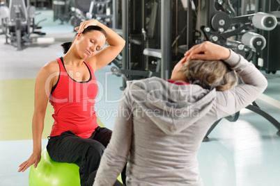 Senior woman with trainer stretching fitness ball