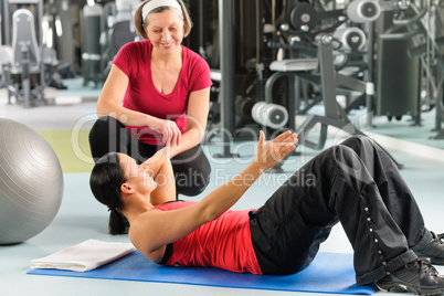 Personal trainer show abdominal exercise on mat
