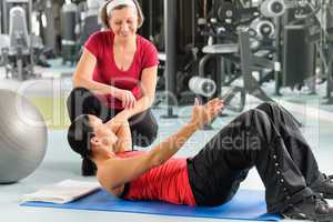 Personal trainer show abdominal exercise on mat