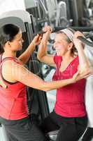 Personal trainer assist senior woman at gym