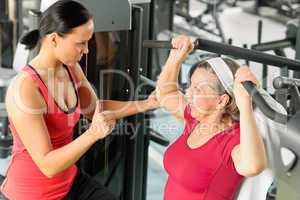 Personal trainer assist senior woman at gym