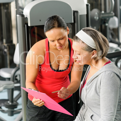 Personal trainer with senior woman at gym