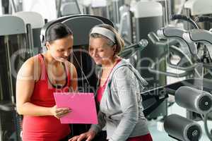 Personal trainer with senior woman at gym