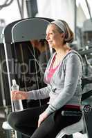 Senior woman relax sitting by fitness machine