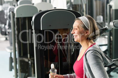 Senior woman relax sitting by fitness machine