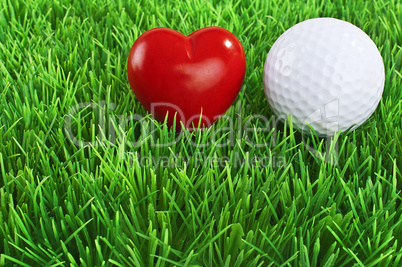 Red heart and white golf ball on the fairway