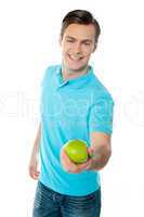 Good looking healthy guy offering a green apple