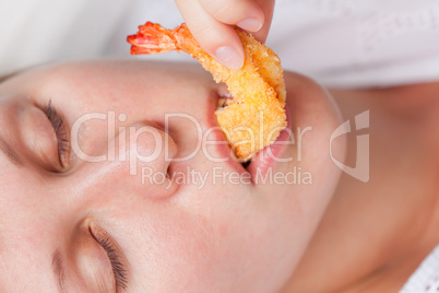 Pretty girl eating grilled shrimp