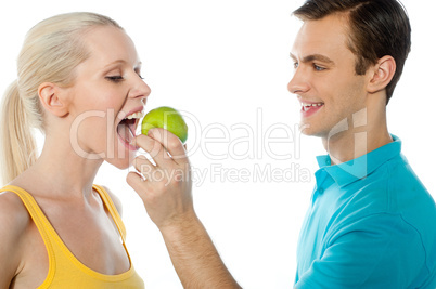 Young guy making her girlfriend eat an apple