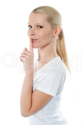 Side view of pretty smiling girl with finger on her lips