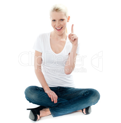 Cute young girl seated on floor and pointing up