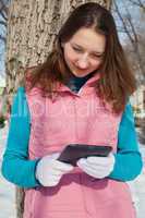 Teen girl with e-book reader in a park