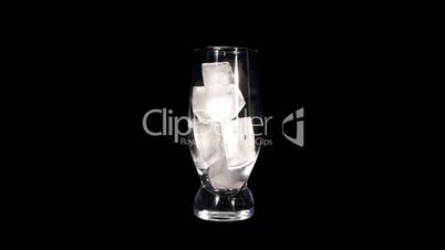 Timelapse of melting ice cubes in a glass against black background