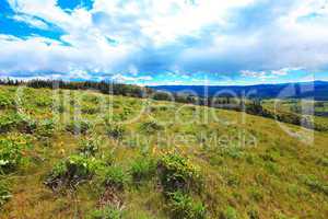 Fields, hills, river and mountains landscape.