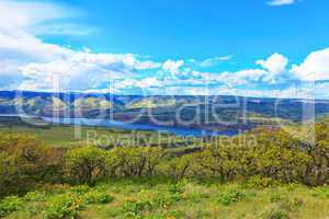 Fields, hills, river and mountains landscape.