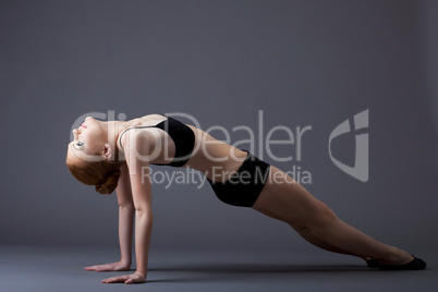 young gymnast girl in black top lay on background