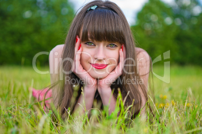 Pretty girl in red sarafan lies on the green grass