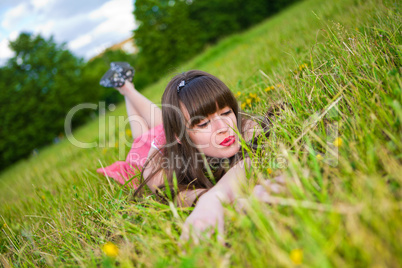 Pretty girl in red sarafan lies on the green grass