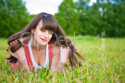 Pretty girl in red sarafan lies on the green grass