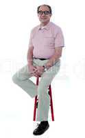 Confident senior man resting on stool