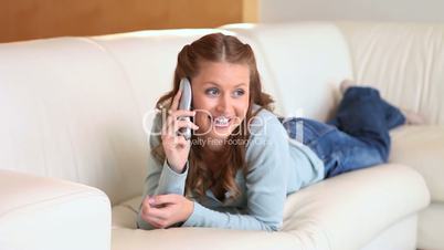 Junge Frau telefoniert auf dem Sofa