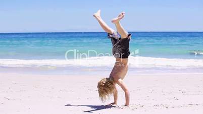 Kind macht einen Handstand am Strand