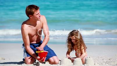 Vater mit Kind bauen eine Sandburg