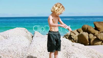 Junge am Strand zwischen Steinen
