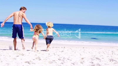 Mann rennt mit seinen Kindern am Strand