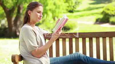 Frau liest Buch in einem Park
