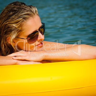 Summer woman lying on yellow floating mattress