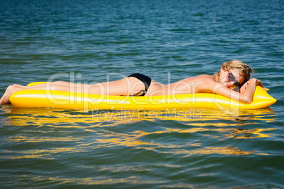 Summer woman floating on yellow water mattress