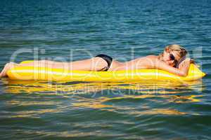 Summer woman floating on yellow water mattress