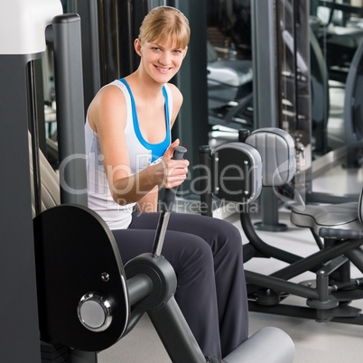 Young woman at fitness center exercise machine