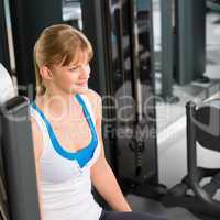 Young woman at fitness center sitting machine